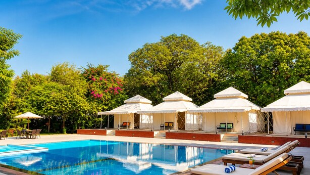 Piscina con sillas de descanso y toldos blancos.
