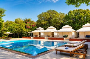Piscina com espreguiçadeiras e toldos brancos.