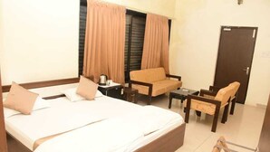 Una habitación de hotel con cama, dos sillas, una mesita y un escritorio con silla.