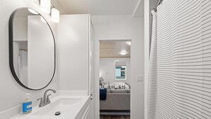 A bathroom with a white sink, mirror, and a bottle of hand soap.