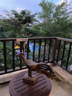 A wooden deck with a railing, a bird sculpture, and a pool in the background.