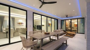 Una sala moderna con una mesa de comedor de madera, sillas de mimbre, un banco y un ventilador de techo.