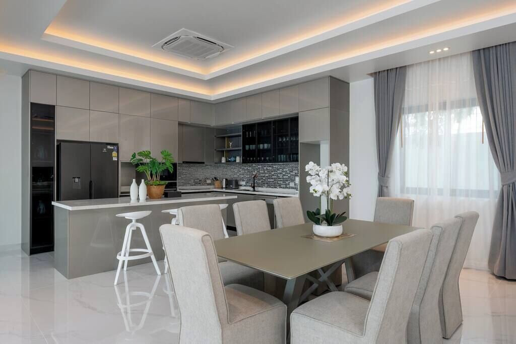 Una cocina moderna con una isla central, taburetes de bar y una mesa de comedor con sillas.
