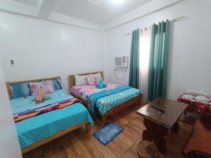 Una habitación pequeña con dos camas, una mesa y una cortina.