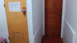 Un pasillo estrecho con una puerta de madera y un pequeño banco.