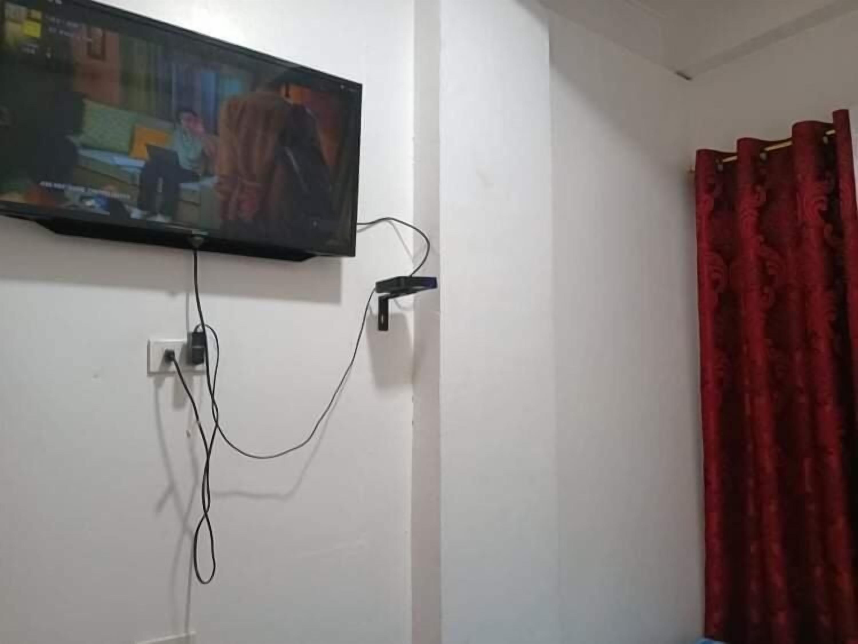 A television mounted on a wall with a visible power cord.