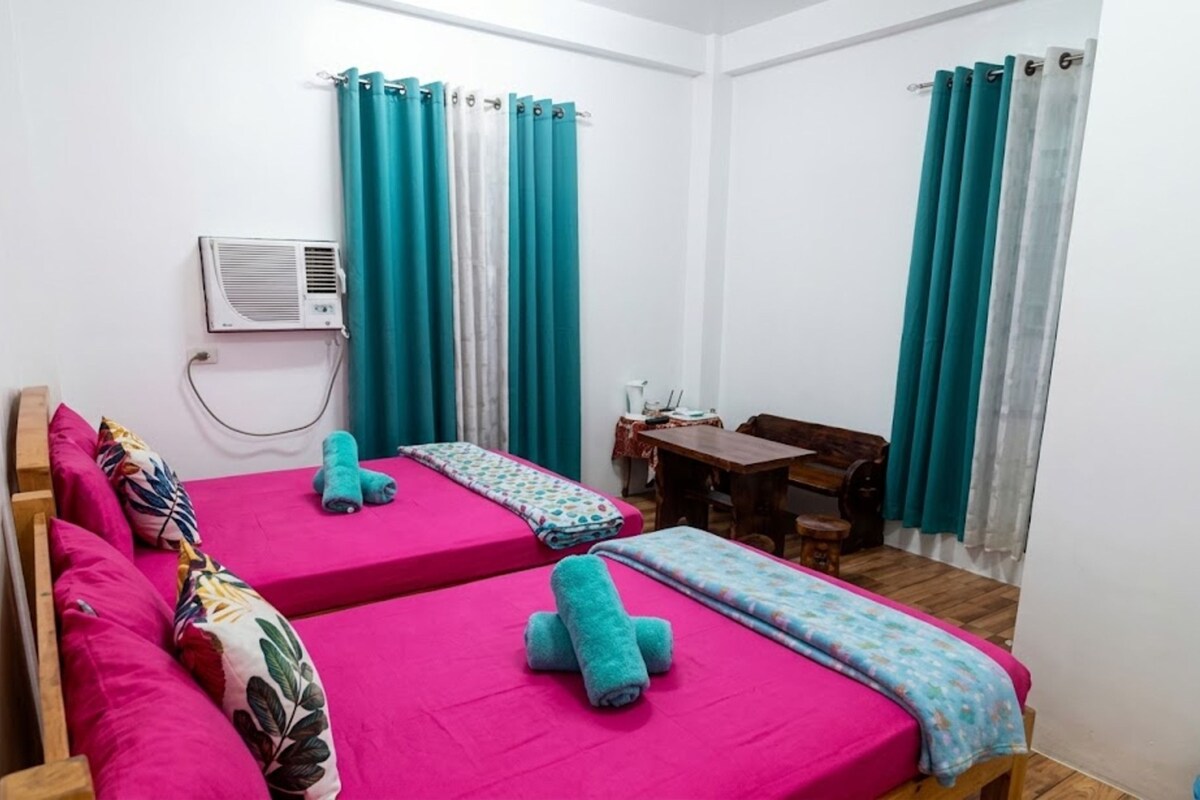 A room with two beds, a desk, and a chair.