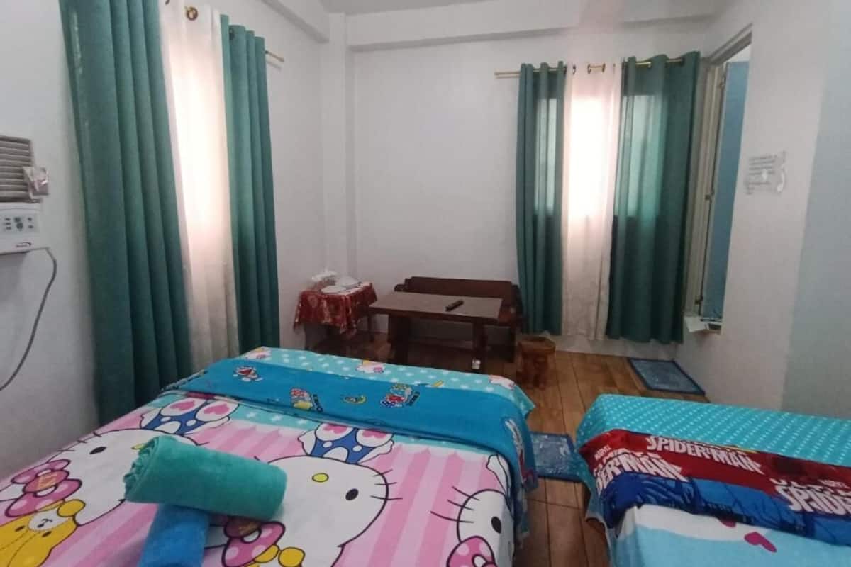A room with two beds, a desk, and a chair.