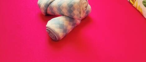 A bed with a red mattress and a rolled-up blanket.