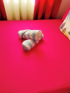 A bed with a red mattress and a rolled-up blanket. - MJ Home (Taguig)
