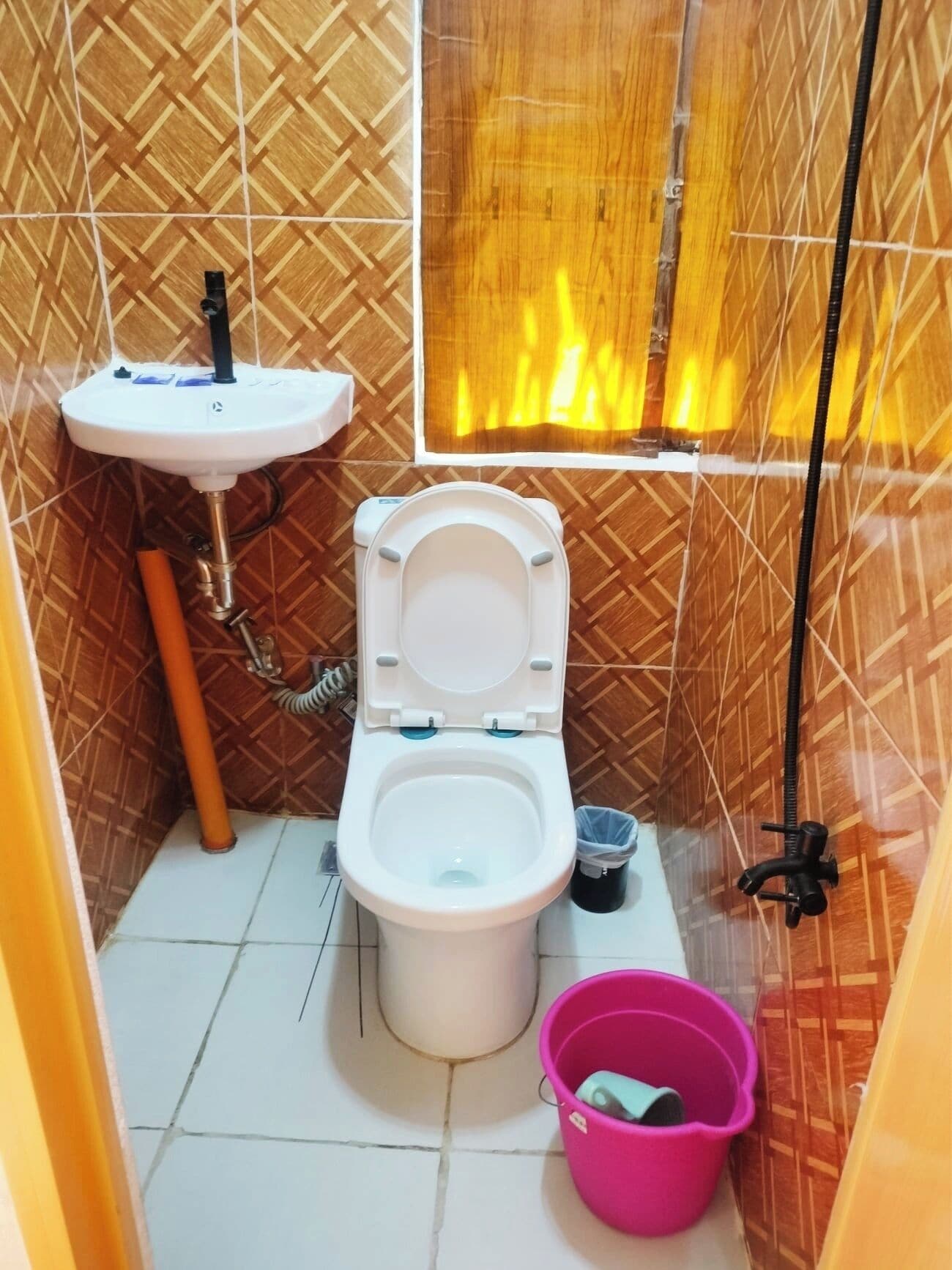A bathroom with a toilet, sink, and a window with a view of a fire.