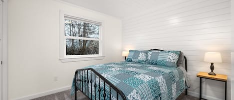 Ett sovrum med en säng, två sänglampor, ett fönster med utsikt och en taklampa.