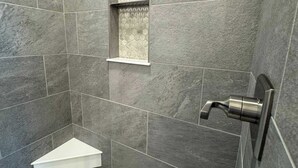 A bathroom with grey tiles, a white sink, and a shower with a hexagonal pattern. - Adorable Downtown Cottage - Walk to Shops & Cafes! (Palmer)