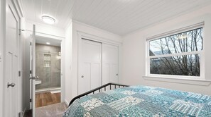 Ein Schlafzimmer mit einem Bett, einem Fenster mit Blick, einer Tür und einem Duschbereich.
