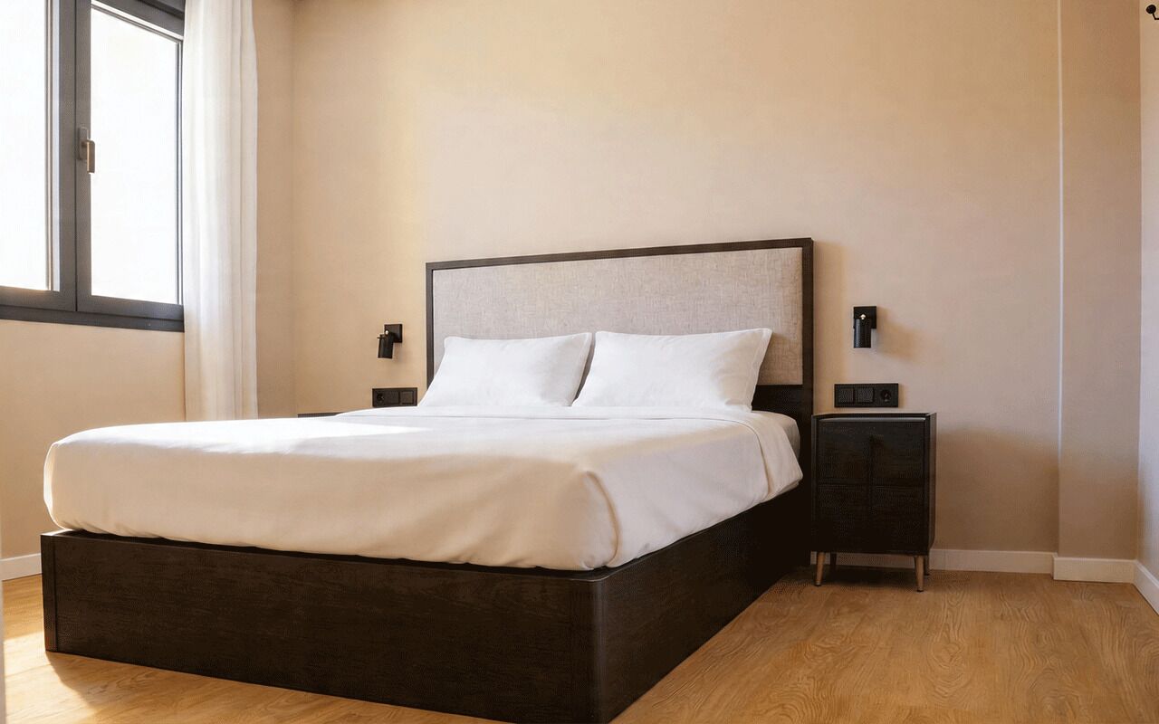 Een moderne slaapkamer met een groot bed, nachtkastjes en een raam met gordijnen.