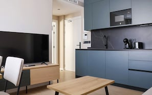 Een moderne keuken met een magnetron, een koffieapparaat en een flatscreen televisie.