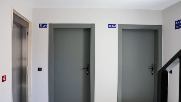 Deux portes fermées, portant les numéros 201 et 202, un détecteur d’incendie et un escalier.