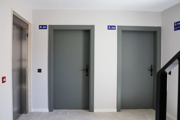 Dos puertas cerradas con los números 201 y 202, un detector de incendios y una escalera.