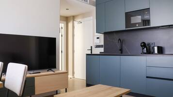 A modern kitchen with a flat-screen TV, a coffee machine, and a microwave.