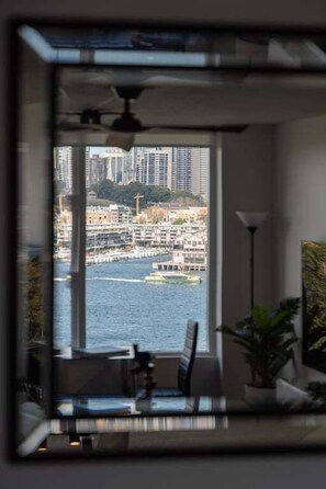 A room with a large window overlooking a cityscape with buildings and a body of water. - The Postcard - Harbour Bridge & Opera House Views (North Sydney)
