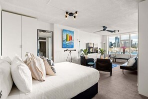 A modern hotel room with a large bed, a desk, and a view of the city. - The Postcard - Harbour Bridge & Opera House Views (North Sydney)