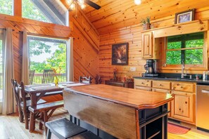 Ein Holzhütten-Interieur mit Küche, Essbereich und großen Fenstern.