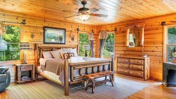 Une chambre dans une cabane en bois, avec un lit, un banc en bois, une commode et un ventilateur de plafond.