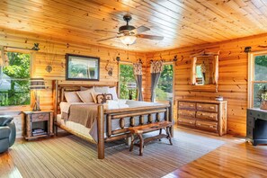 Ein Schlafzimmer einer Holzhütte mit einem Bett, einer hölzernen Bank, einer Kommode und einem Deckenventilator.