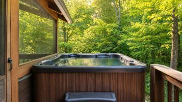 Un bain à remous sur une terrasse en bois, avec vue sur une forêt.