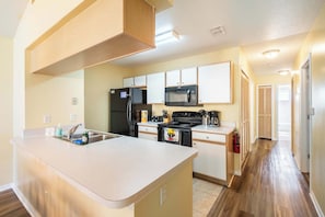 A modern kitchen with a central island, built-in appliances, and a wooden ceiling. - ‼️Kissimmee Condo - Sleeps 8, Private Balcony (Kissimmee)