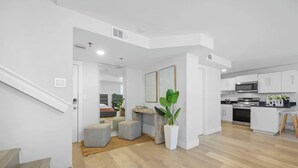 Een modern appartement met een keuken, eethoek en een trap naar een ander niveau.