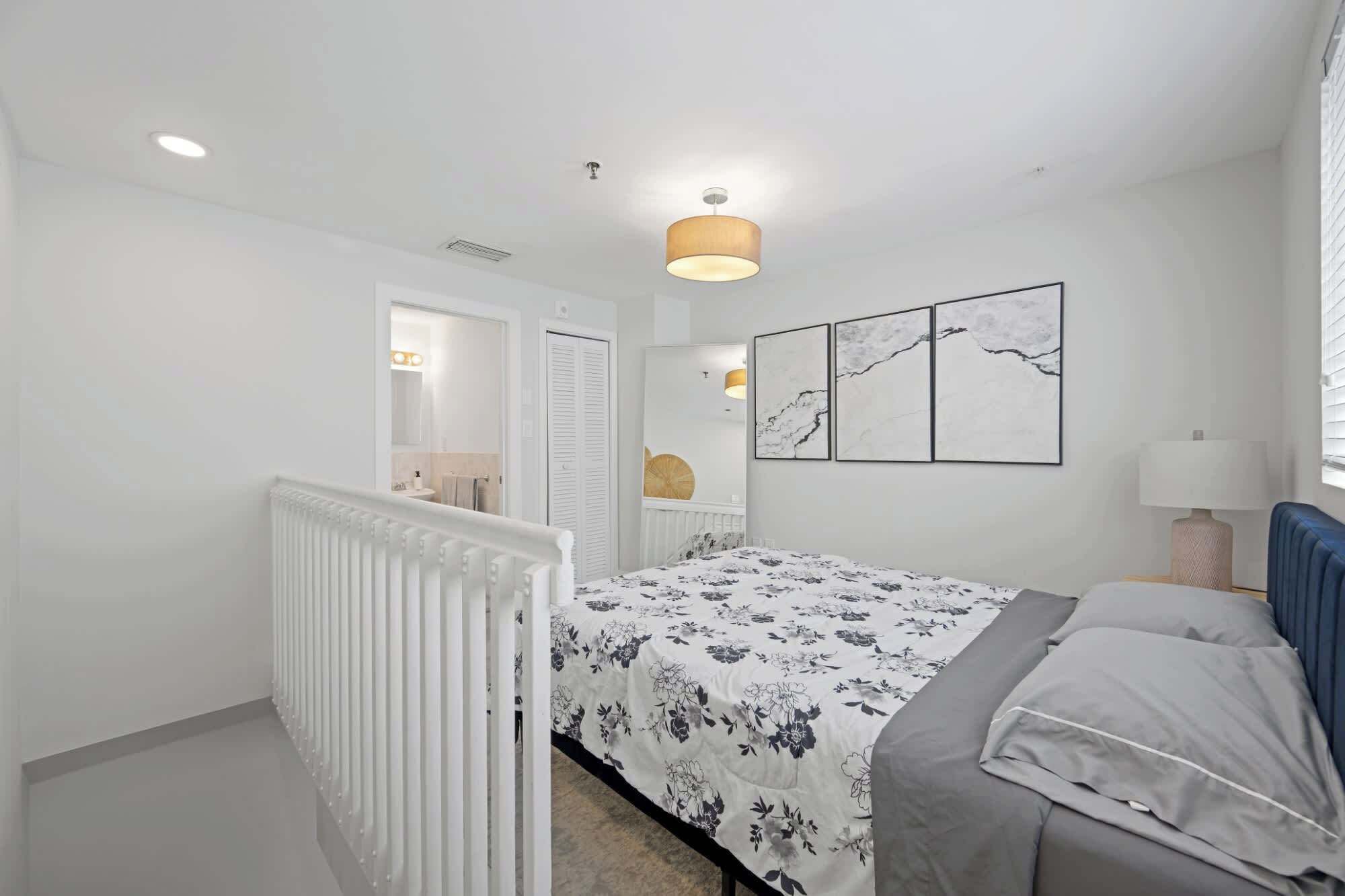 A bedroom with a bed, a radiator, a wall-mounted lamp, and a ceiling light.