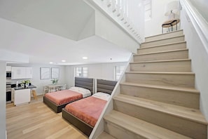 Eine moderne Wohnung mit Treppe, zwei Betten, einer Küche und einem Essbereich.
