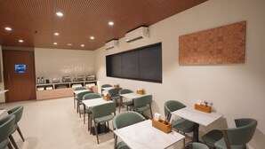 A dining area with green chairs and white tables, a wooden ceiling, and a large patterned wall. - Hotel Jubilee Park Hitech city (Hyderabad)