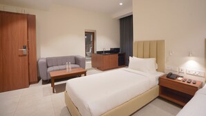 A hotel room with a bed, a sofa, a desk, a small kitchenette, and a wardrobe. - Hotel Jubilee Park Hitech city (Hyderabad)