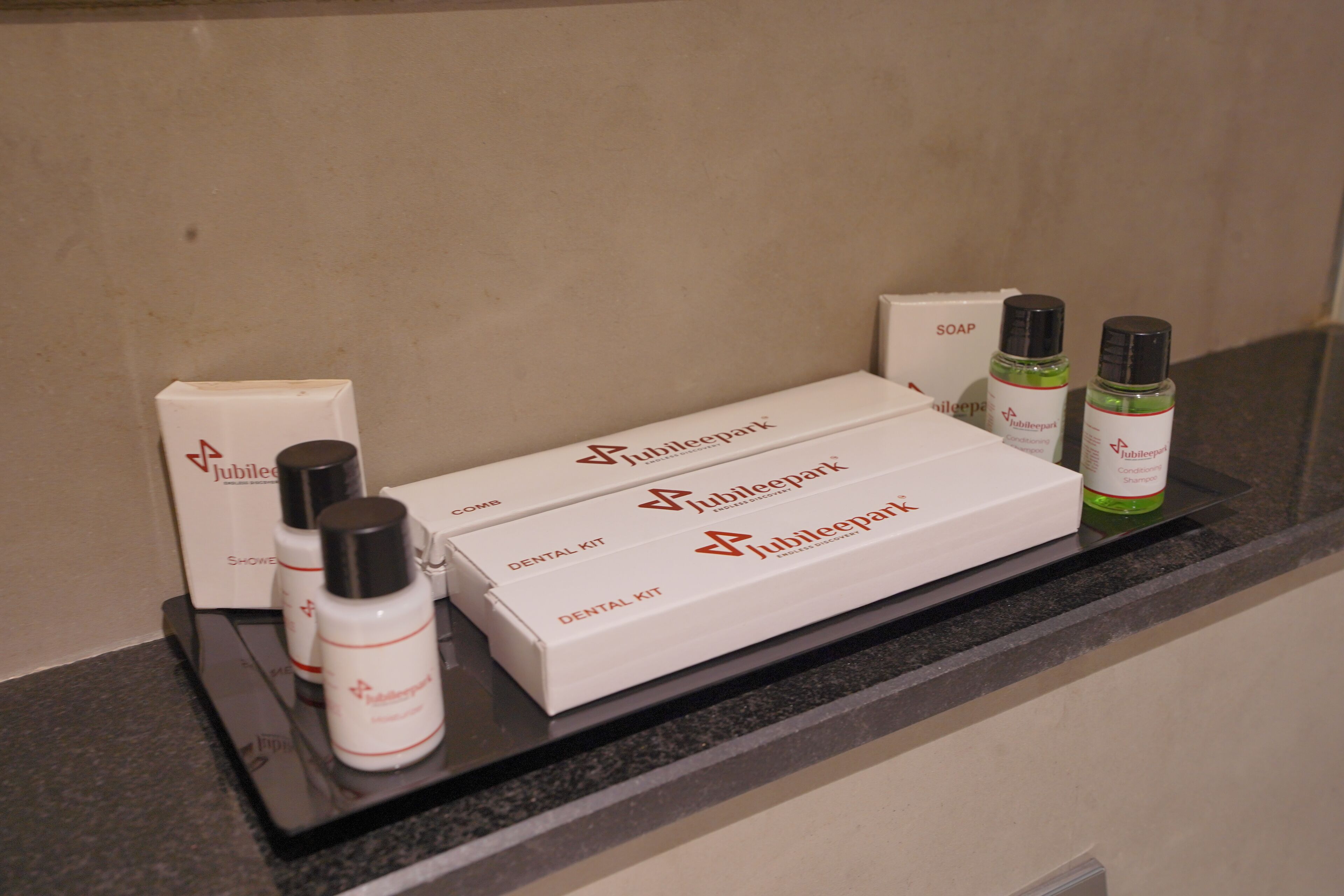 Un comptoir de salle de bain d’hôtel avec une trousse de toilette, du savon et des flacons de shampoing.