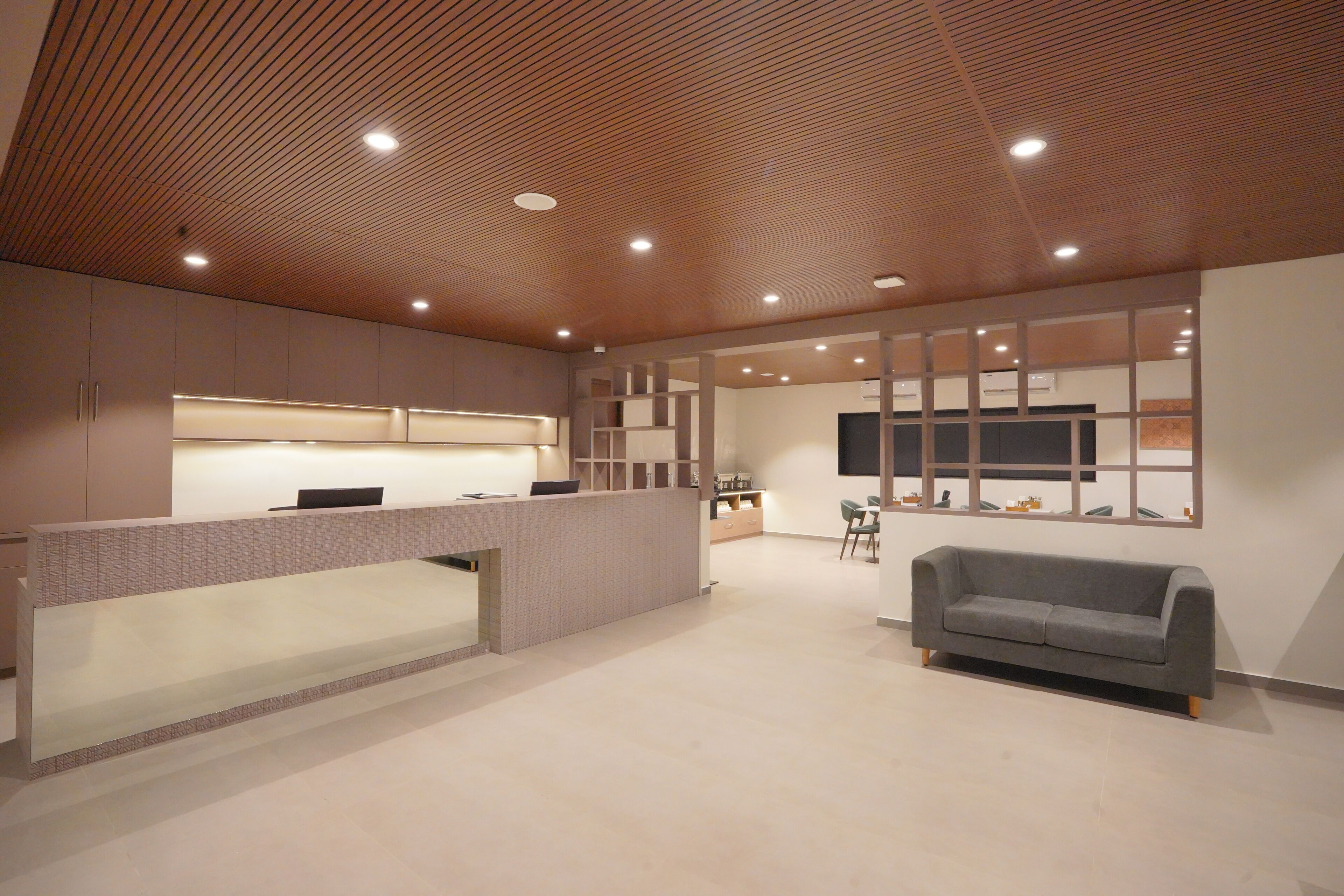 A reception area with a reception desk, a sofa, and a TV mounted on the wall.