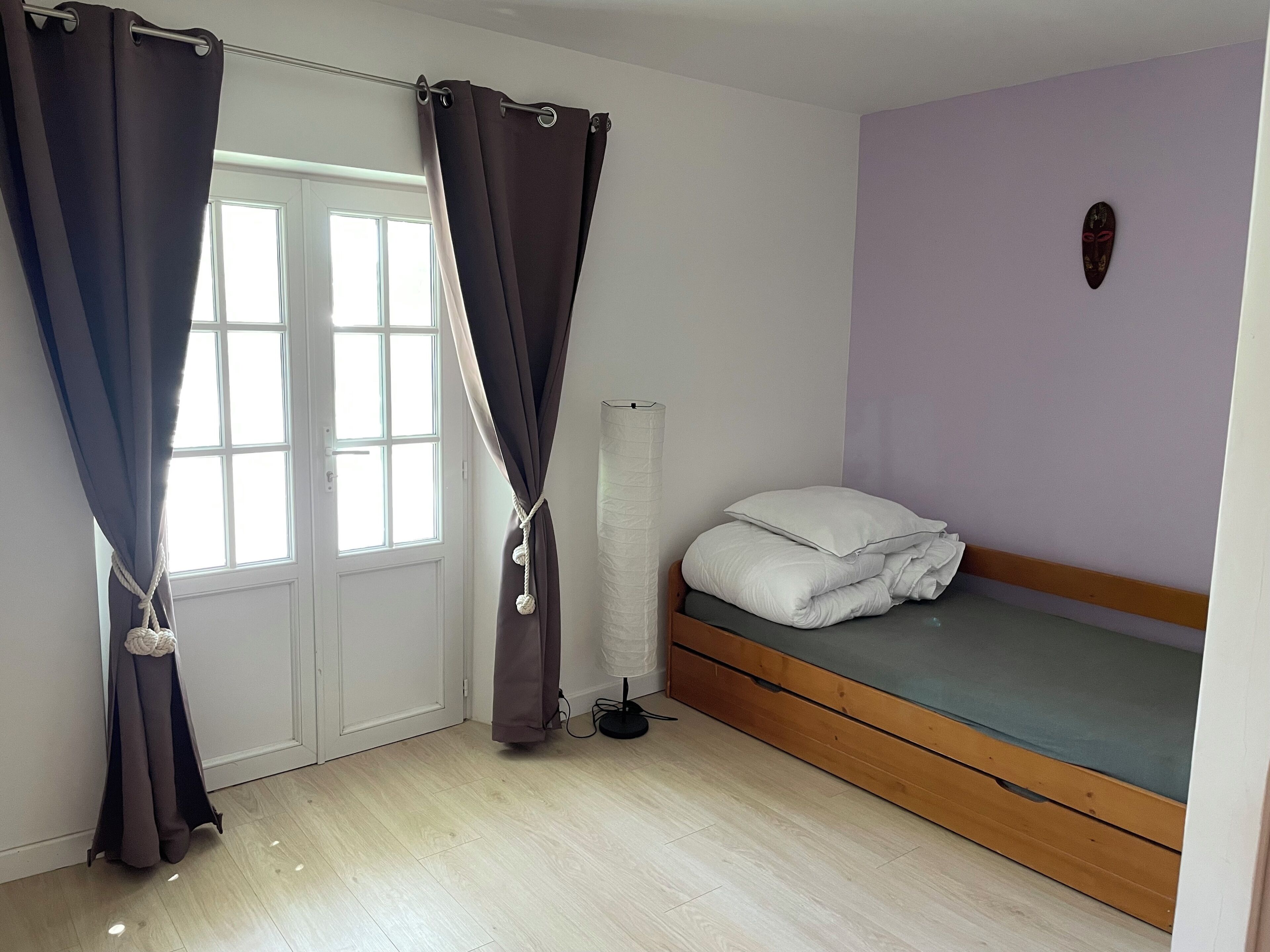 A bedroom with a bed, curtains, a radiator, and a window.