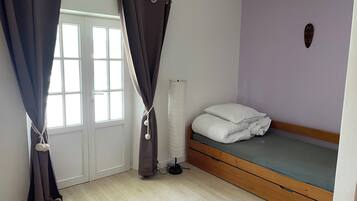 A bedroom with a bed, curtains, a radiator, and a window.