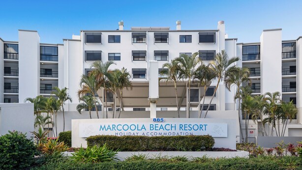 Un edifici modern d'alguns pisos amb un rètol que diu 'Marcola Beach Resort'.