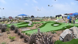 Un camp de mini golf amb un prat verd, fosses de sorra i una zona de posada.