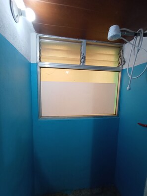 A room with a blue wall, a window with a metal frame, and a ceiling light fixture. - Yellow House (Antigua Guatemala)