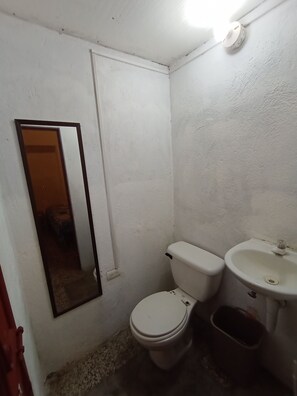 A small, white-walled bathroom with a toilet, sink, and a mirror. - Yellow House (Antigua Guatemala)