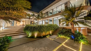 A modern building with a glass facade, outdoor steps, and tropical plants. - LegKo Villa (Pecatu)