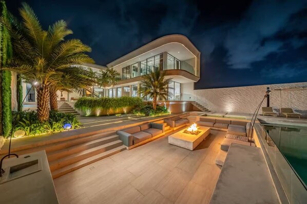 A modern house with a pool, outdoor seating, and palm trees. - LegKo Villa (Pecatu)