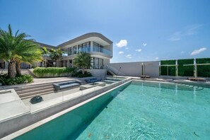 A modern building with a swimming pool, outdoor seating, and palm trees. - LegKo Villa (Pecatu)