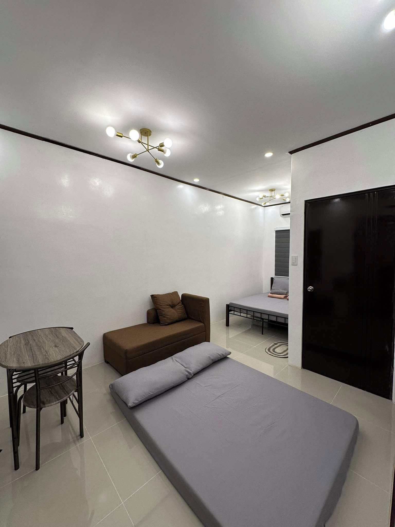 Una habitación moderna con una cama, un sofá, una mesita y un escritorio.