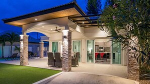 A covered outdoor patio with stone pillars, a ceiling fan, and a dining area with chairs. - Orchid Paradise Homes OPV513 (Hin Lek Fai)