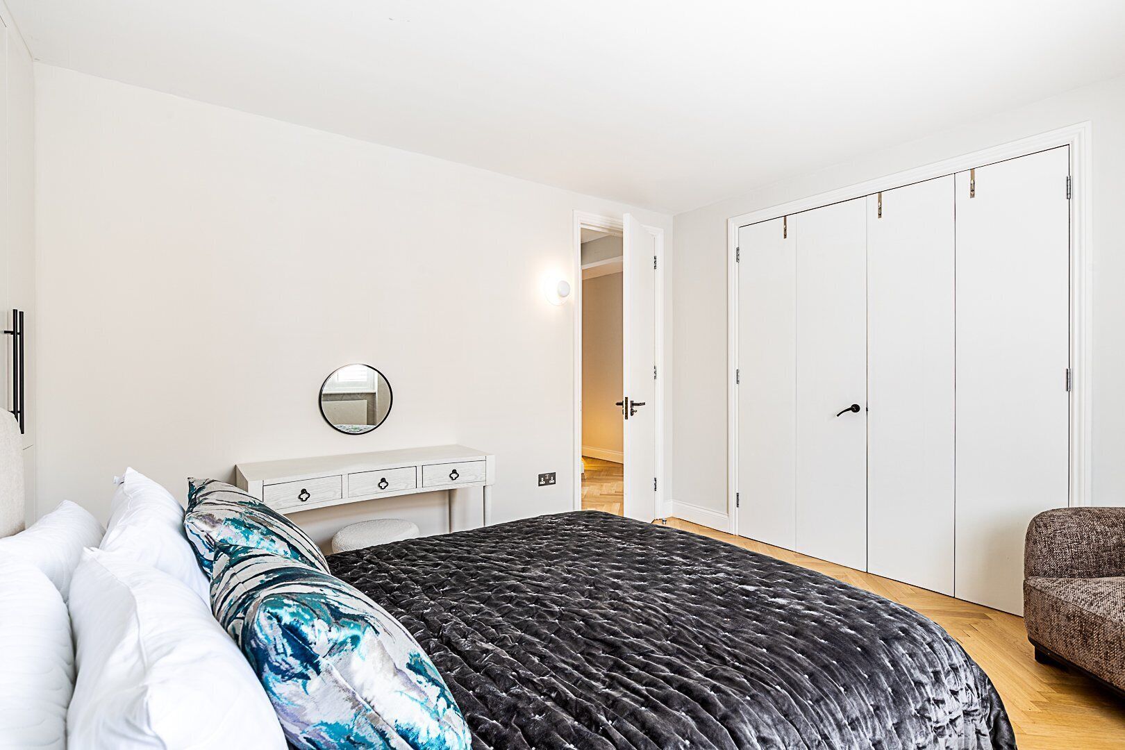 Ein Schlafzimmer mit Bett, Kommode, Spiegel und Kleiderschrank.