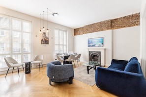 A modern living room with a fireplace, dining area, and large windows. - Stylish Marylebone/Baker St Retreat (London)